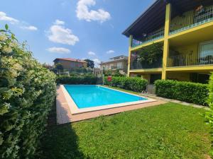 a swimming pool in a yard next to a building at Sandra Apartment in Lonato del Garda