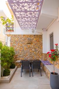 a patio with two chairs and a table and a stone wall at City Compass Luxury Suites in Rhodes Town