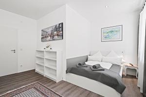 a white bedroom with a bed and a shelf at Appartment Maria Friedrichshafen Bodensee in Friedrichshafen