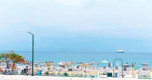 einen Strand mit Liegestühlen und Sonnenschirmen und dem Meer in der Unterkunft SeaSTAR Beach Apartments in Kos-Stadt