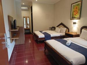 デンパサールにあるCatur Adi Putraのベッド2台とテレビが備わるホテルルームです。