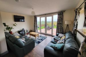 a living room with two couches and a large window at Norfolk Coastal Cottages in Heacham