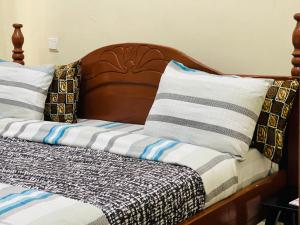 Bett mit einem Kopfteil aus Holz und Kissen darauf in der Unterkunft Virunga Homes in Ruhengeri