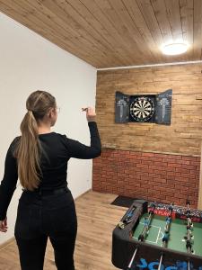 a woman is pointing at a dart board on a wall at Chata Javor in Kežmarok