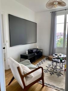 ein Wohnzimmer mit einem Flachbild-TV und einem Stuhl in der Unterkunft Cinéma privé/ Proche Paris/Orly in Athis-Mons