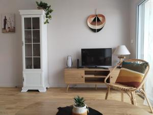 un soggiorno con TV e sedia di Appartement neuf classé, balcon et petite vue mer a Pléneuf-Val-André