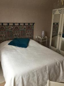 een slaapkamer met een wit bed en een blauw kussen bij Maison entière Trélévern in Trélévern