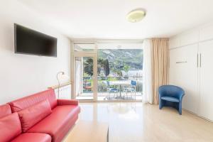 sala de estar con sofá rojo y silla azul en Residence Casa al Sole Apartments, en Nago-Torbole