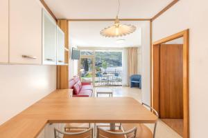 cocina y sala de estar con mesa de madera y sillas en Residence Casa al Sole Apartments, en Nago-Torbole