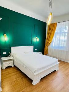 a bedroom with a white bed and a green wall at Sí Apartments Aquapark in Oradea