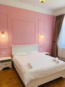 a bedroom with pink walls and a bed with towels on it at Sí Apartments Aquapark in Oradea