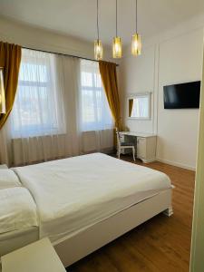 a bedroom with a large white bed and a desk at Sí Apartments Aquapark in Oradea