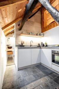 uma cozinha com armários brancos e tectos em madeira em Het Kostershuisje em Nuenen
