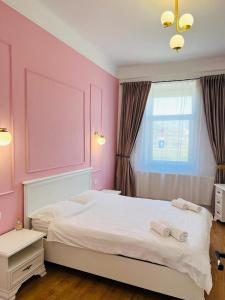 a bedroom with a large bed with pink walls at Sí Apartments Aquapark in Oradea