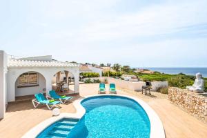 uma villa com piscina e vista para o oceano em Villa Belvedere em Cala'n Porter
