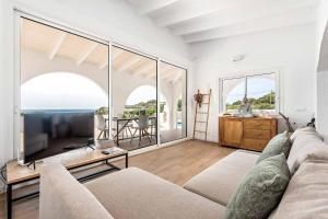 a living room with a couch and a television at Villa Belvedere in Cala en Porter