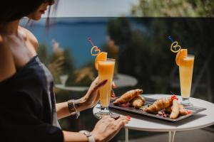 a woman holding a tray of food on a table with drinks at Villa Arausa in Vodice