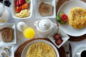 a table topped with plates of breakfast foods and orange juice at Sea Breeze Candidasa in Candidasa +33 photos