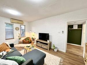 a living room with a couch and a tv at Immaculate Stylish Apartment in South Hedland