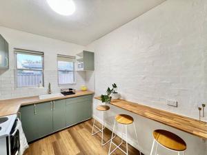 a kitchen with a counter and stools in it at Immaculate Stylish Apartment in South Hedland