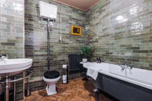 a bathroom with a tub and a toilet and a sink at Russell Court by Orenda-Luxe in Llandudno