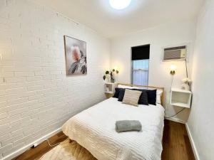Un dormitorio con una pared de ladrillo blanco y una cama en Immaculate Stylish Apartment, en South Hedland