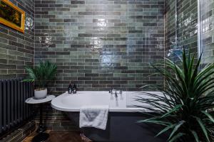 a bathroom with a bath tub and two plants at Russell Court by Orenda-Luxe in Llandudno