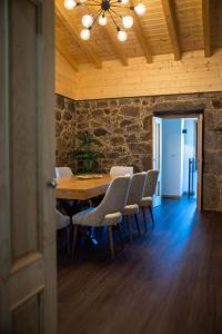 a dining room with a table and chairs and a stone wall at Casa Gondiga in Roriz
