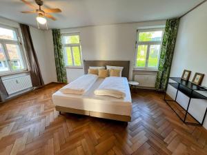 a bedroom with a large bed with wooden floors and windows at Auszeit im Bad Diezlings in Hörbranz