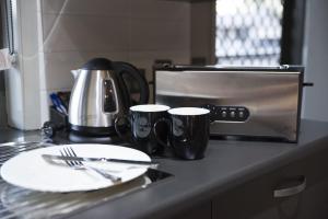 a table with a plate and two mugs on a counter at The Rocks Motel in Charleville