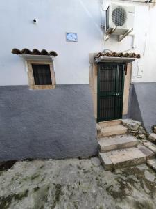 eine grüne Tür in einem weißen Gebäude mit Treppen in der Unterkunft Nonna Elena in Rodi Garganico