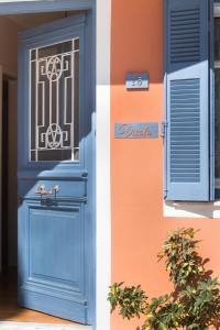 una porta blu su un edificio con finestra di Vicolo Appartamenti Locali by Imagine Lefkada a Città di Lefkada