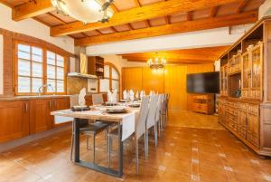 a kitchen with a long table with chairs and a television at Cal Ramon con piscina in Rubí