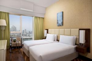 a hotel room with two beds and a window at La Suite Dubai Hotel & Apartments in Dubai