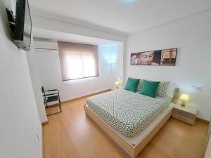 a bedroom with a bed with green pillows and a window at Céntrico apartamento en Valencia próximo parada de metro Ángel Guimerà in Valencia