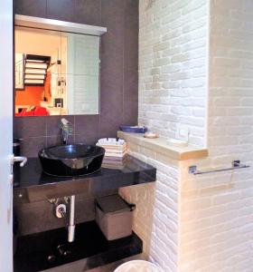 a bathroom with a black sink and a brick wall at Regina Viarum Apartment, Historic City Centre in Brindisi
