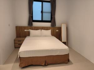 1 dormitorio con 1 cama grande y ventana en 成功99民宿-成功久久-成功66民宿2館, en Taitung