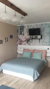 a bedroom with a large bed with a tv on the wall at Szeged Pu-Ma Apartman in Szeged
