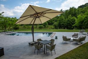 Cruna di Subida Wine Country House في كورمونس: طاولة وكراسي مع مظلة بجوار حمام السباحة