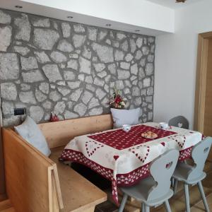 Cuore delle Dolomiti Alloggi Vacanze في سان بيترو دي كادوري: غرفة طعام مع طاولة وجدار حجري