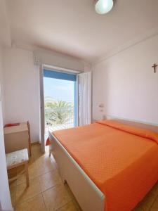 a bedroom with an orange bed and a large window at Hotel Dinarica in Marotta
