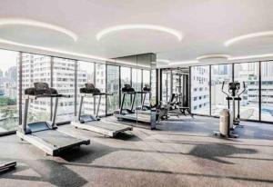 a gym with several tread machines in a room with windows at Modern room,Sky pool, BTS Asok,Sukhumvit in Bangkok