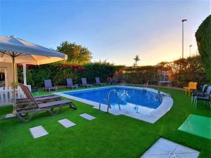 una piscina en un patio con sillas y sombrilla en Ibis Jerez De La Frontera Cadiz, en Jerez de la Frontera