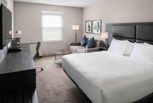 um quarto de hotel com uma cama grande e um sofá em The Inn at Burlington, Trademark Collection by Wyndham em Burlington