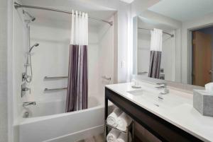 a bathroom with a sink and a tub and a shower at The Inn at Burlington, Trademark Collection by Wyndham in Burlington