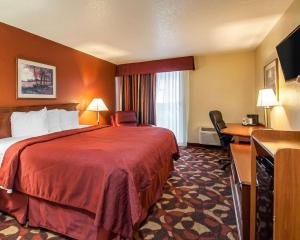 a hotel room with a large red bed and a desk at Quality Inn & Suites Kansas City I-435N Near Sports Complex in Kansas City