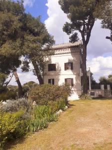 a large white house with trees in a field at Torre Marinella in Ostuni
