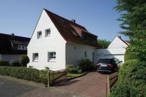 ein weißes Haus mit einem Auto in der Einfahrt in der Unterkunft Gemütliches Haus mit großem traumhaften Garten in Bremen
