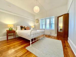 une chambre avec un lit blanc et une fenêtre dans l'établissement Barton Cottage, à Katoomba