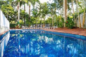 a large blue swimming pool with chairs and palm trees at Oscar on Main resort Walk to beach and Tedder Ave in Gold Coast